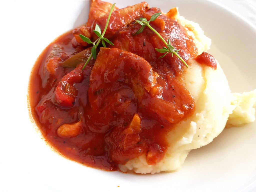 a close up of mash covered with a red stew