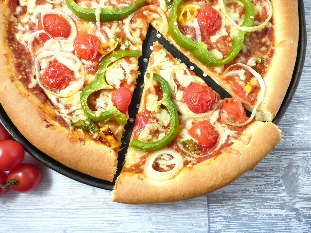 Overhead view of a spelt crust pizza with a cut slice