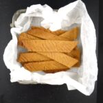 overhead view of toffee cookies in baking paper on a black background