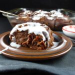 a close up of a chocolate cinnamon bun with white icing