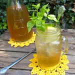 picture of a glass filled with elderflower cordial garnished with mint and lemons