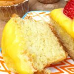 close up of a cupcake topped with lemon curd frosting and a strawberry