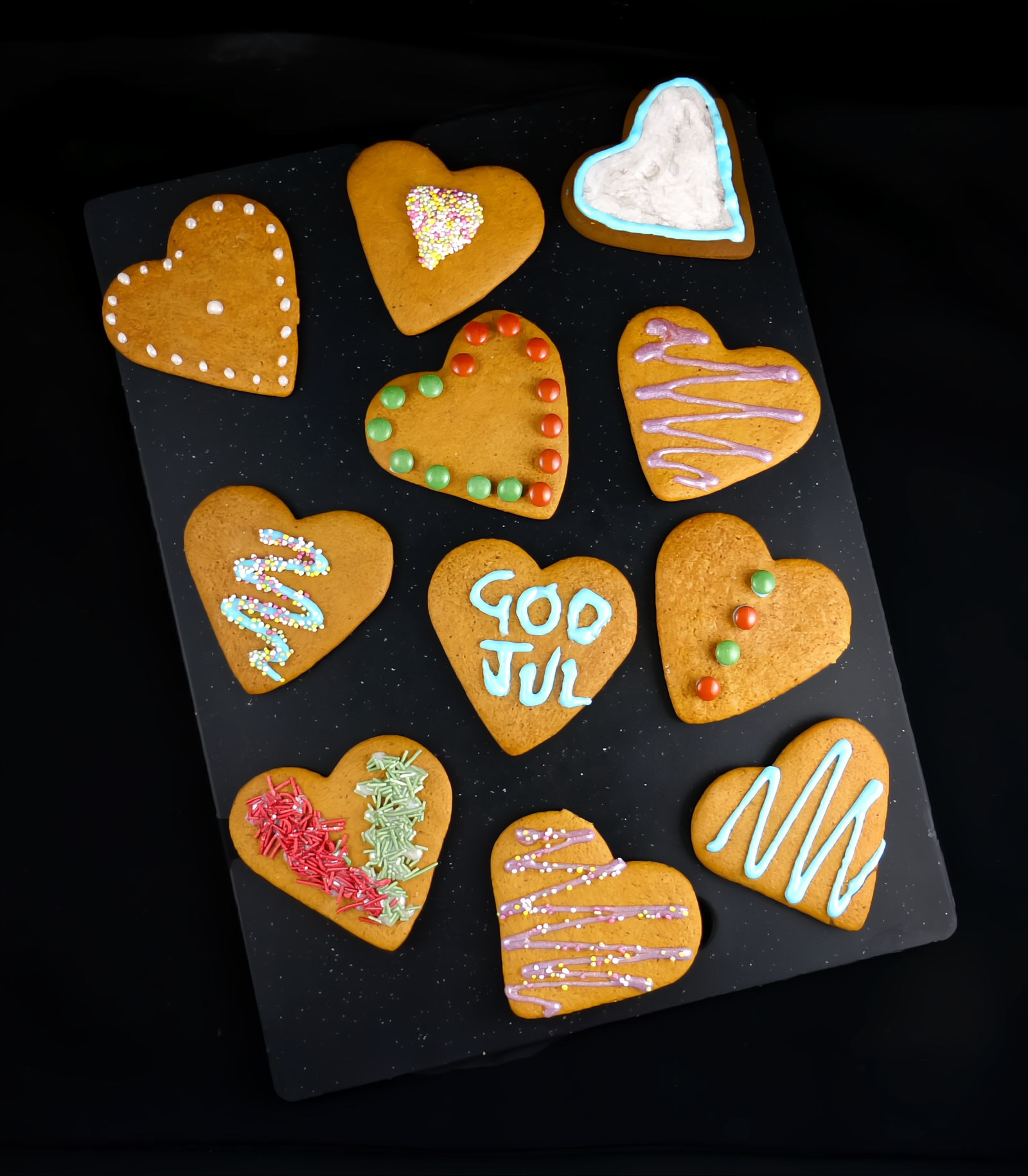 Overhead shot of Swedish pepparkakor decorated on a black surface