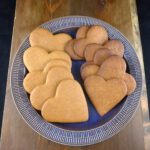 heart-shaped Swedish pepparkakor on a blue plate on top of a wooden board