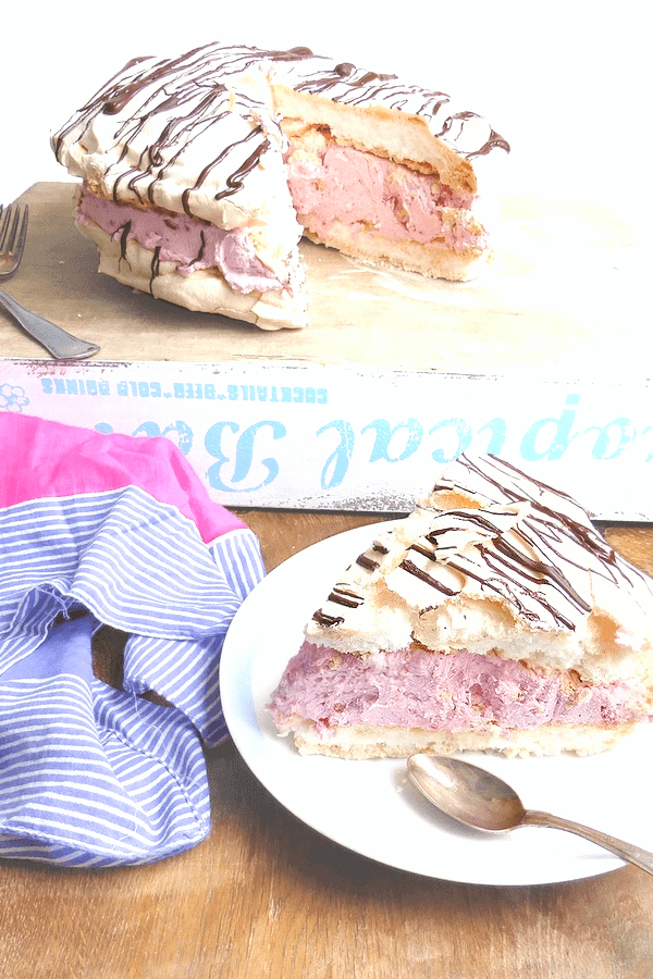 meringue filled with raspberry cream filling on a small place with a spoon on a wooden table