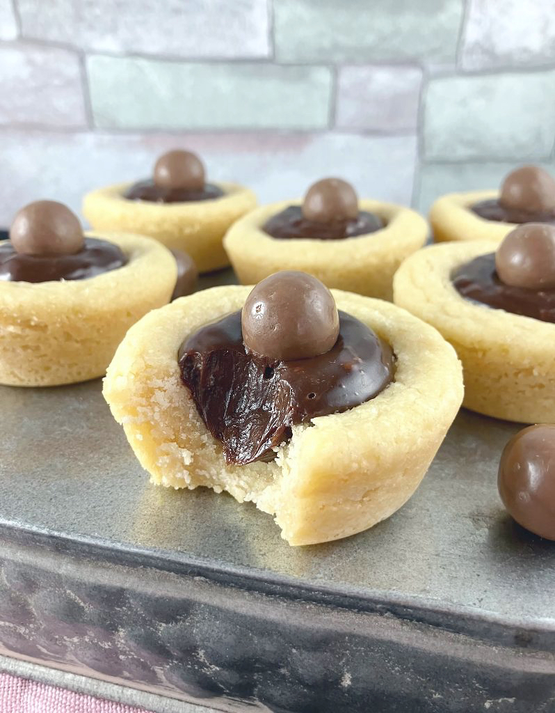 Cookie cups filled with Nutella ganache on a silver blue box with a colorful tile affect behind