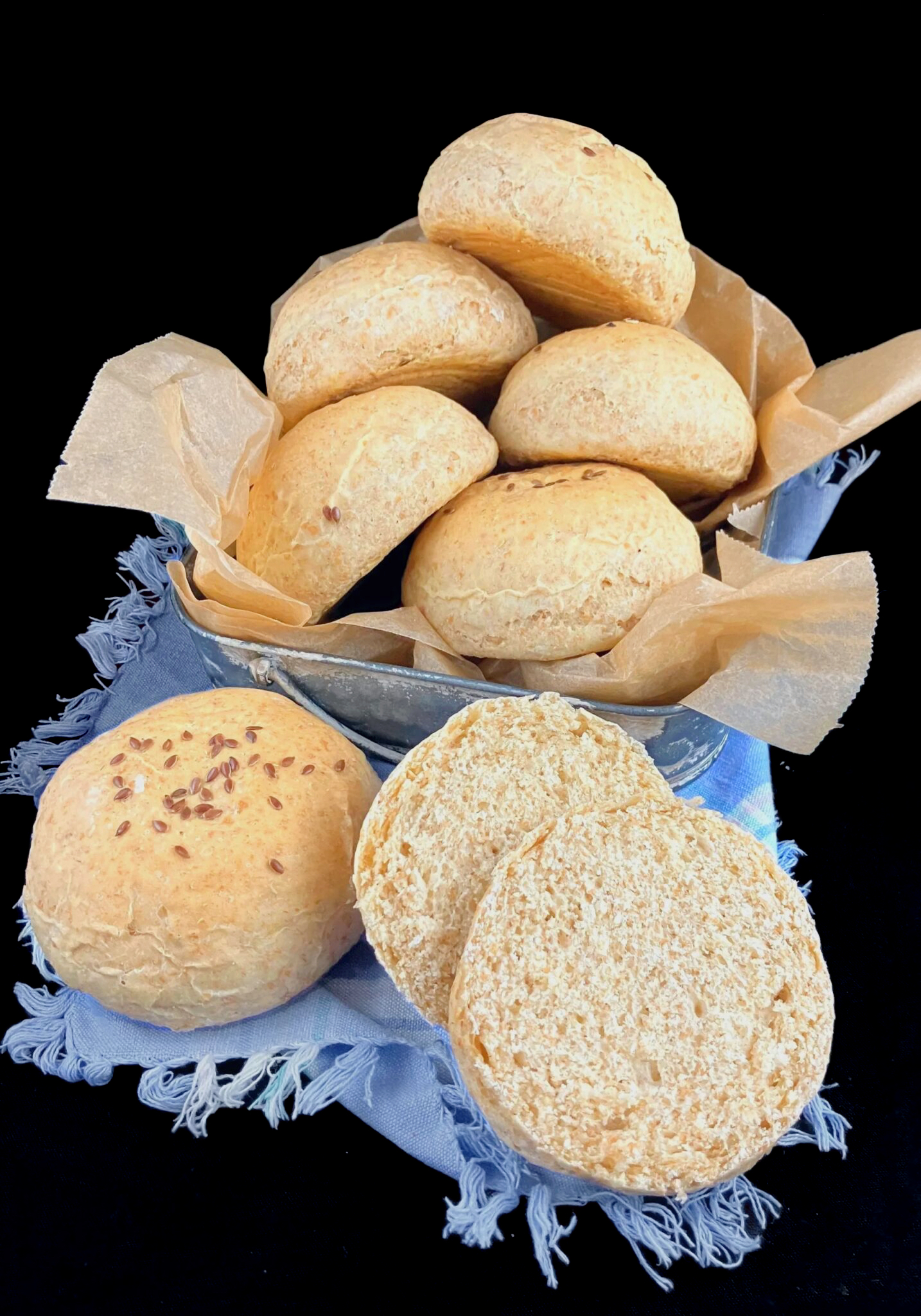 Wholegrain spelt bread buns made with cooked oats on a blue cloth with a dark background.