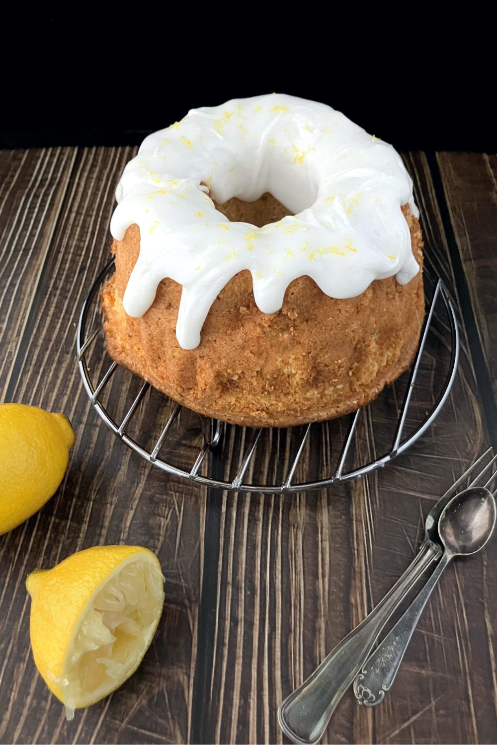 whole lemon and cottage cheese spelt bunt cake side view on a wire rack on top of a wooden affect board