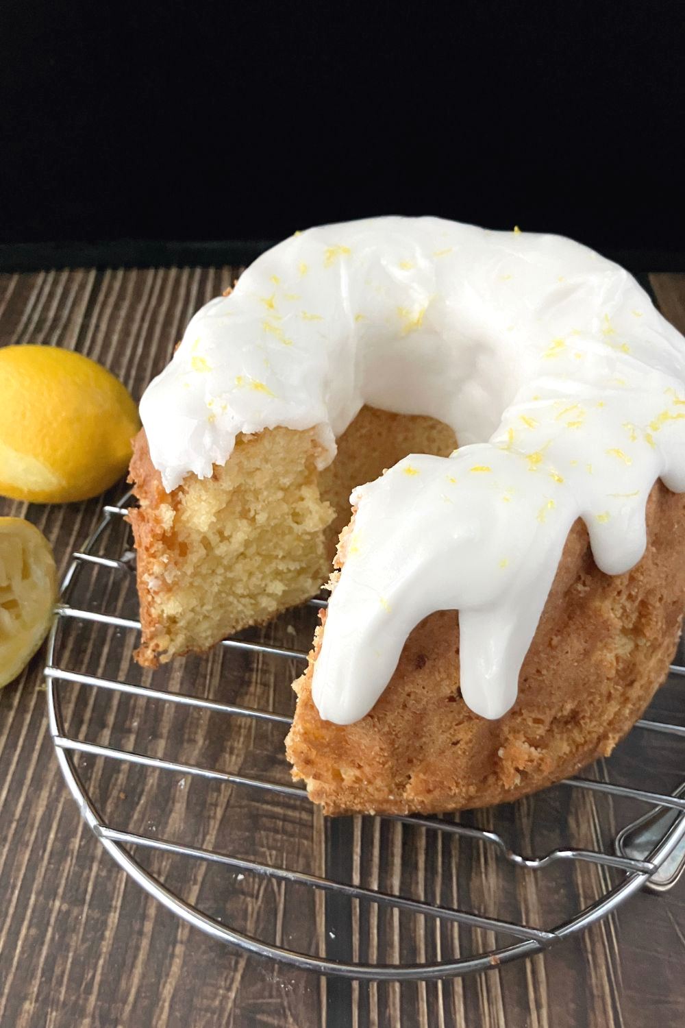 whole lemon and cottage cheese spelt bunt cake side view on a wire rack on top of a wooden affect board