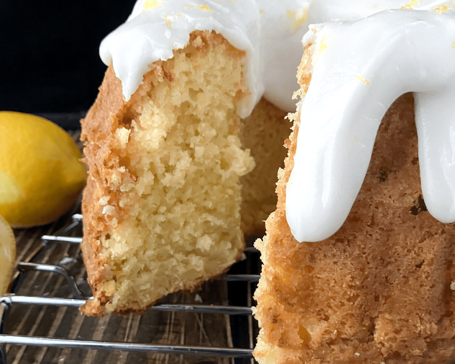 whole lemon and cottage cheese spelt bunt cake side view on a wire rack on top of a wooden affect board