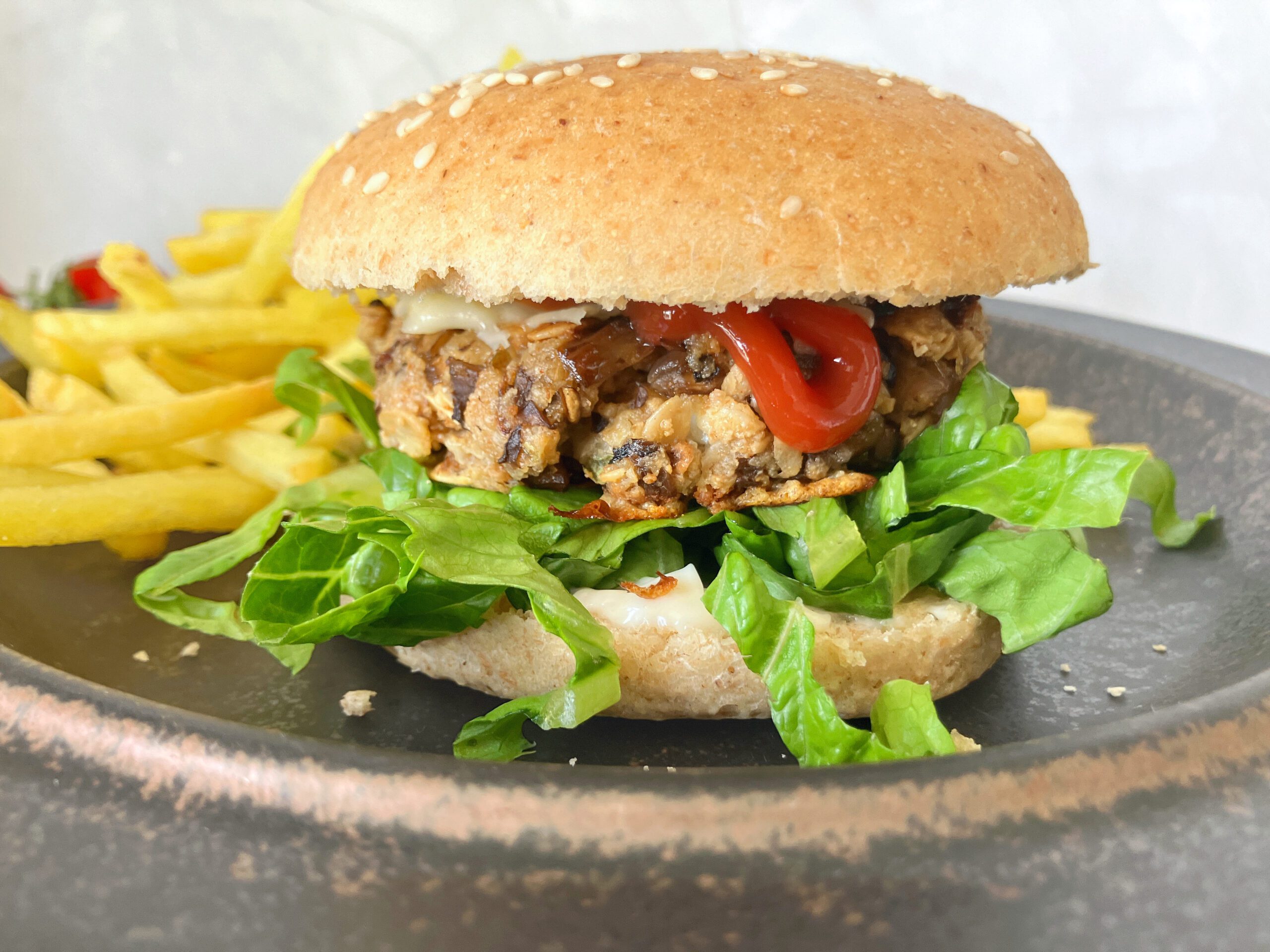 Hearty mushroom burger in a homemade spelt bun, accompanied by golden fries.