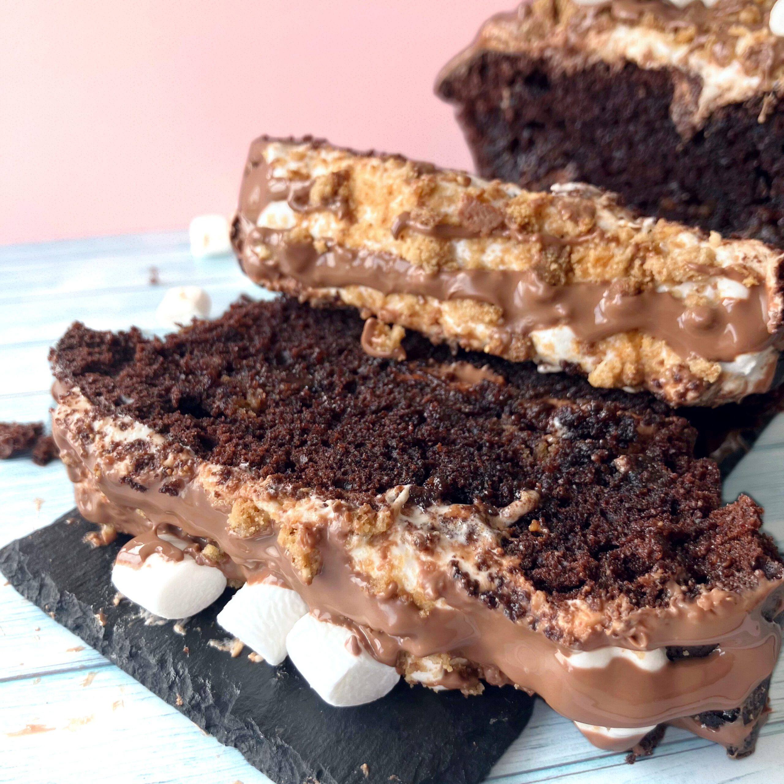 Slice of s’mores cake showing sticky melted marshmallows and softened crushed cookies inside