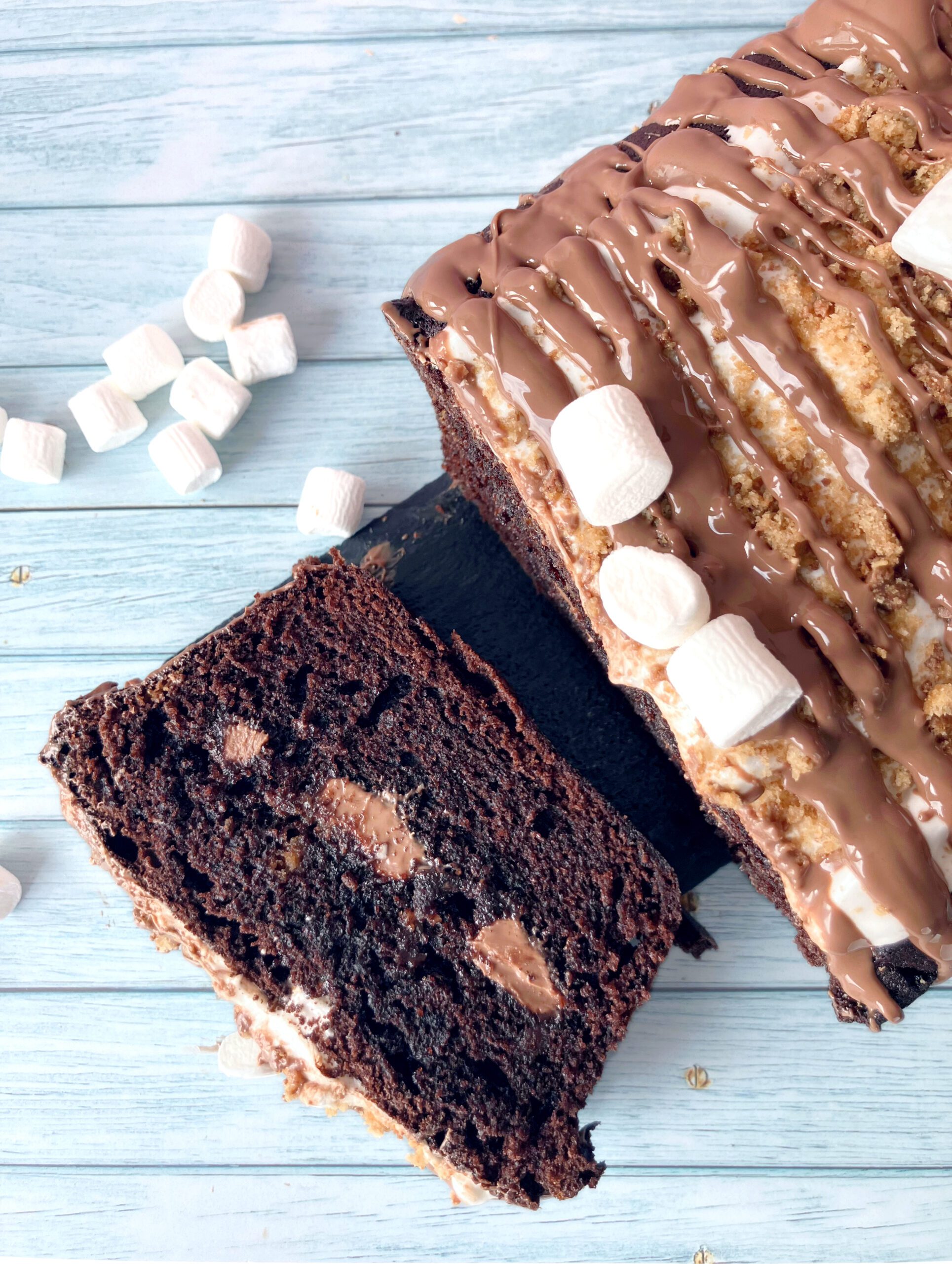 Slice of s’mores cake showing sticky melted marshmallows and softened crushed cookies inside