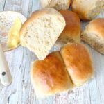 One Hour Spelt Dinner Rolls - small bread buns on a pale blue surface with a bowl of butter and a knife