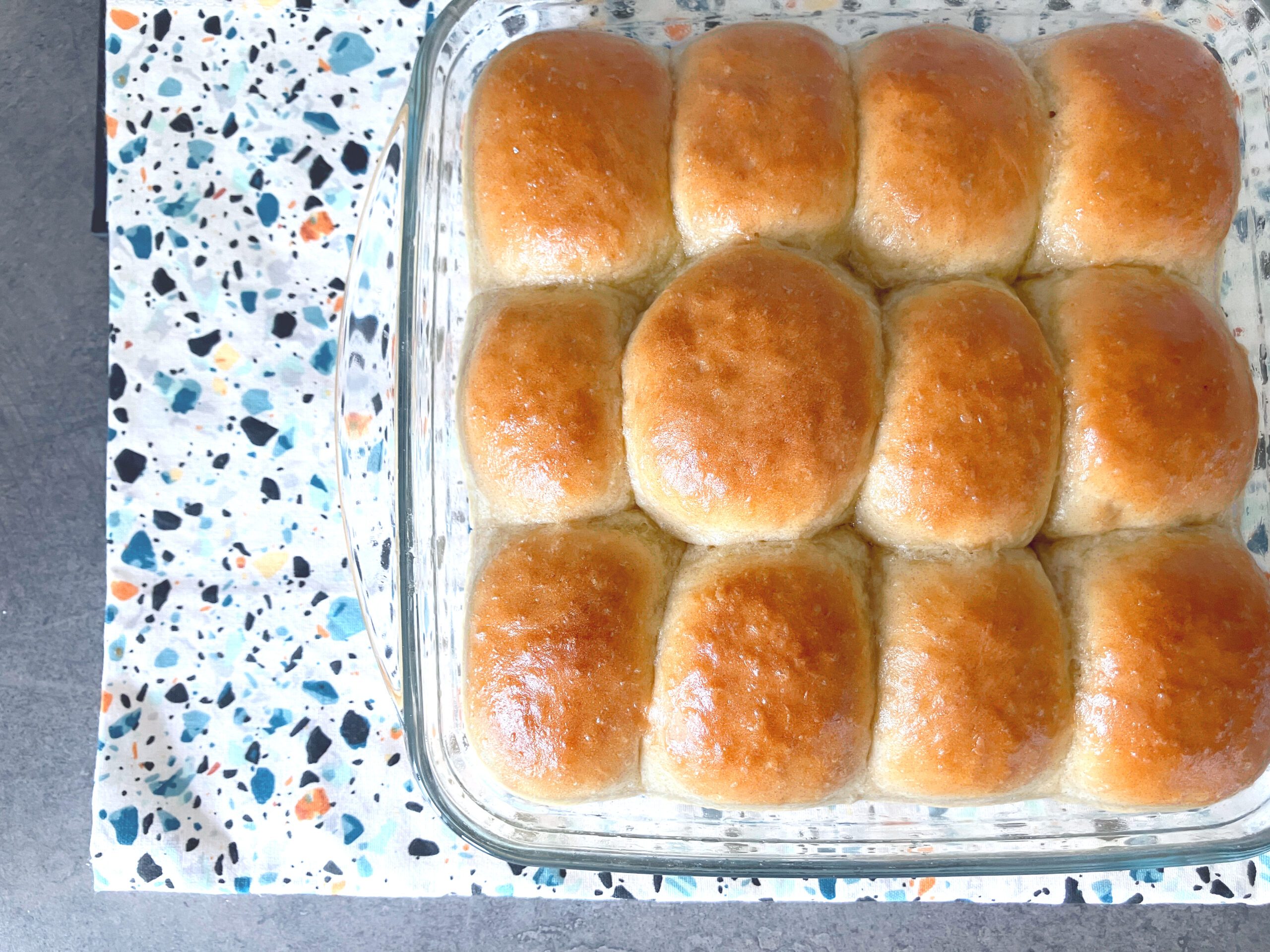 12 one hour bread buns in a glass dish on a colourful cloth