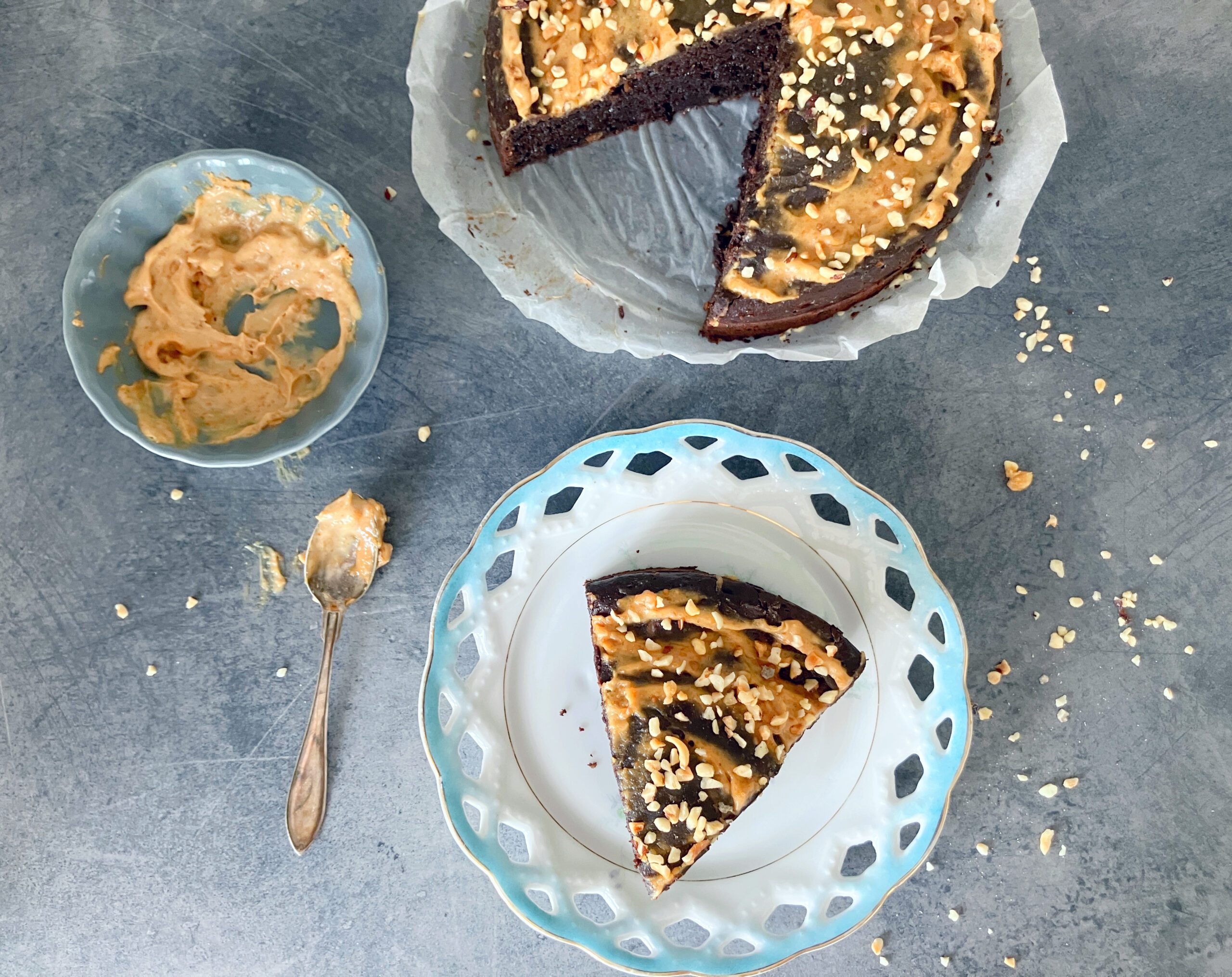 Overhead view picture of a lighter brownie cake with peanut butter and cottage cheese topped with a light peanut butter frosting and chopped hazelnuts