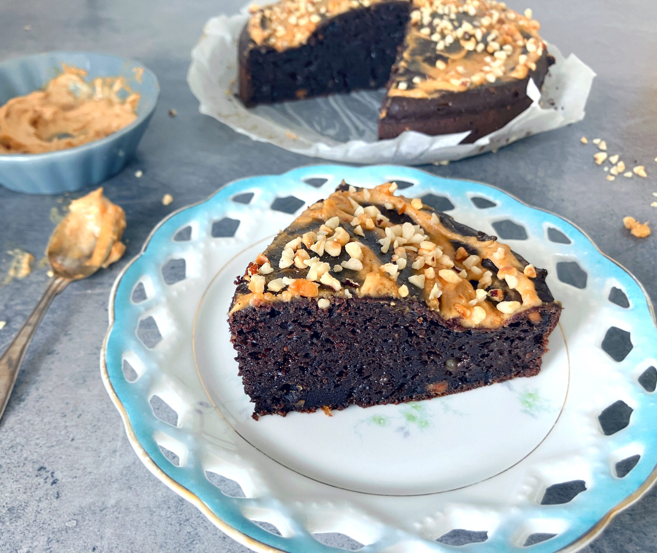 Close up picture of a lighter brownie cake with peanut butter and cottage cheese topped with a light peanut butter frosting and chopped hazelnuts