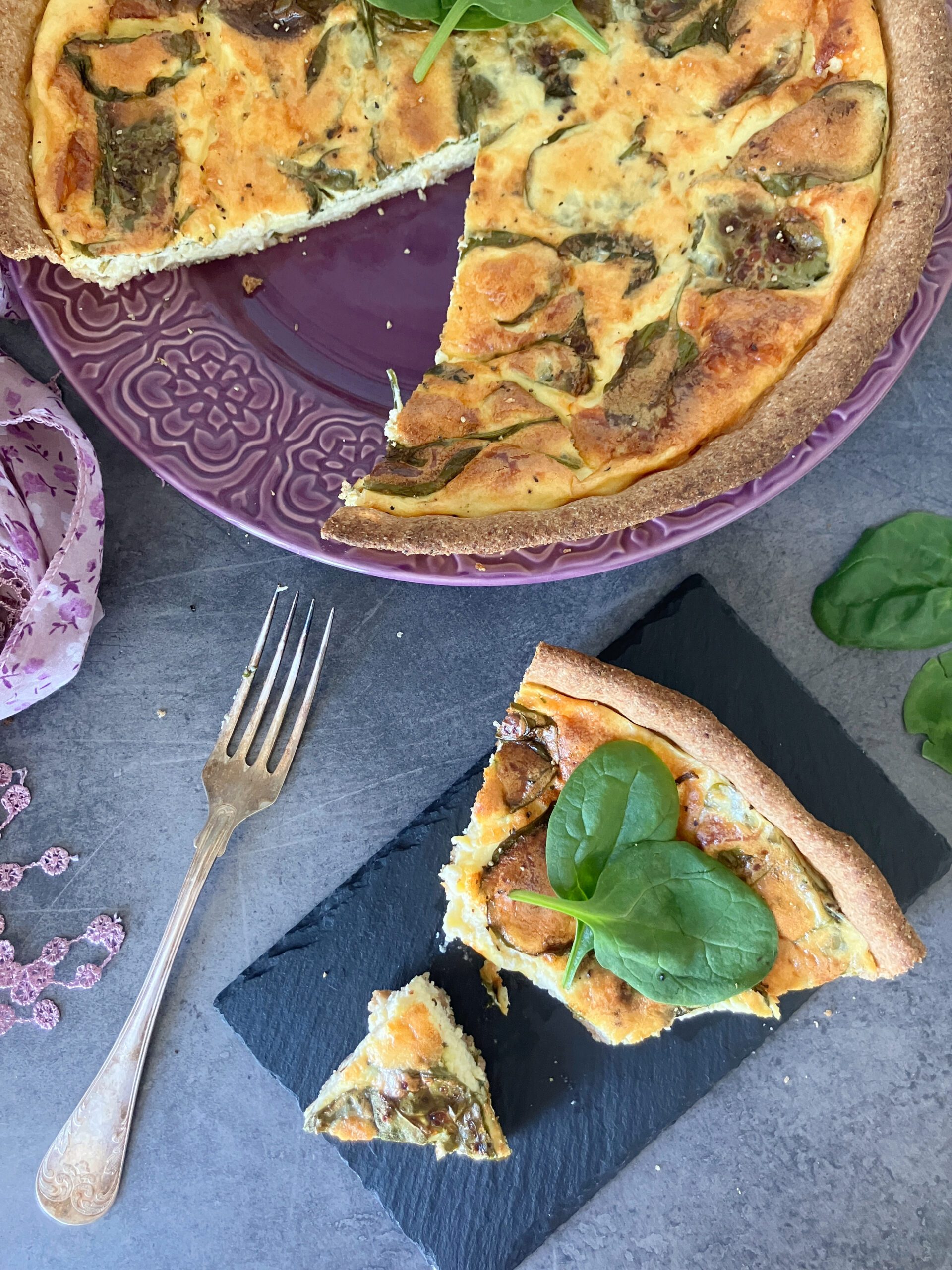Overhead shot of a spelt flour and olive oil crust quiche filled with cottage cheese and Greek yoghurt. A slice is in front of the pie.